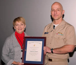 Capt. Brian Durant presents the Navy Meritorious Civilian Service Ward to Kathryn Burns