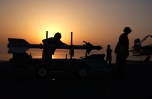 Sidewinder missile on cart shown on flight deck at sunset