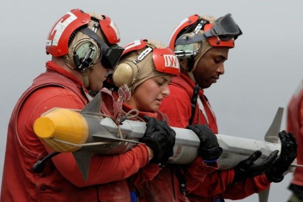 Three Coast Guard members hold an AIM-9X Sidewinder missile
