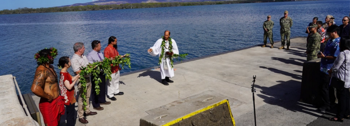 Kahu Kordell Kekoa, center, performs a chant with members of Pearl Harbor Naval Shipyard observing as they stand at the water front of Pearl Harbor.