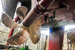 Shipyard workers paint a propeller shaft on the aircraft carrier USS Dwight D. Eisenhower (CVN 69). Dwight D. Eisenhower is undergoing a scheduled docking planned incremental availability at Norfolk Naval Shipyard. (U.S. Navy photo by Mass Communication Specialist Seaman Apprentice Theodore Quintana/Released)