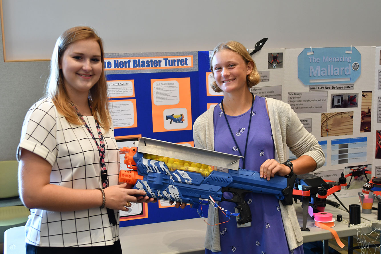 Margot Adams (left) and Chaney Ganninger brief attendees on their integration of a Nerf gun into an autonomous turret gun system. They were among students who completed their summer internships at Naval Surface Warfare Center Dahlgren Division. The Science and Engineering Apprenticeship Program (SEAP) encourages participating high school students to pursue science and engineering careers, to further their education via mentoring by laboratory personnel and their participation in research, and to make them aware of DoN research and technology efforts, which can lead to employment within the DoN.