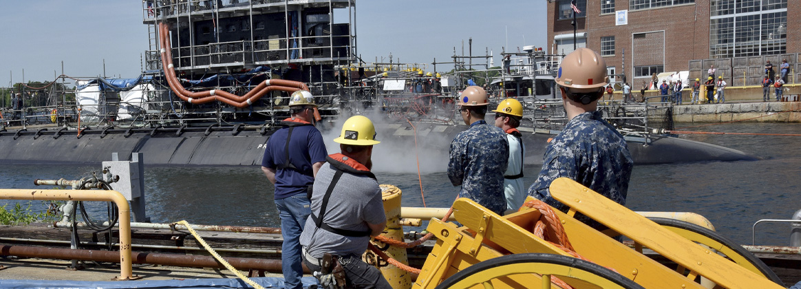 Sailors and Portsmouth Employees overlook the arrival of a waterborne  US Submarine 